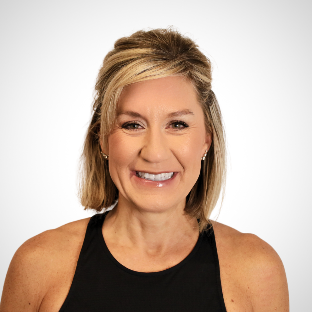 Smiling woman with short blonde hair wearing a black sleeveless top, neutral light background (portrait headshot).